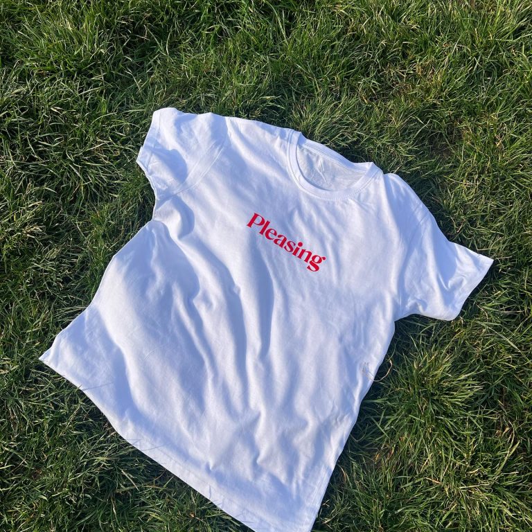 თეთრი-მაისური-pleasing-წარწერით Stagi Group, სტაგი ჯგუფის თეთრი მაისური, Pleasing, წითელი წარწერით, ხავერდის დიზაინი, ბალახის ფონზე