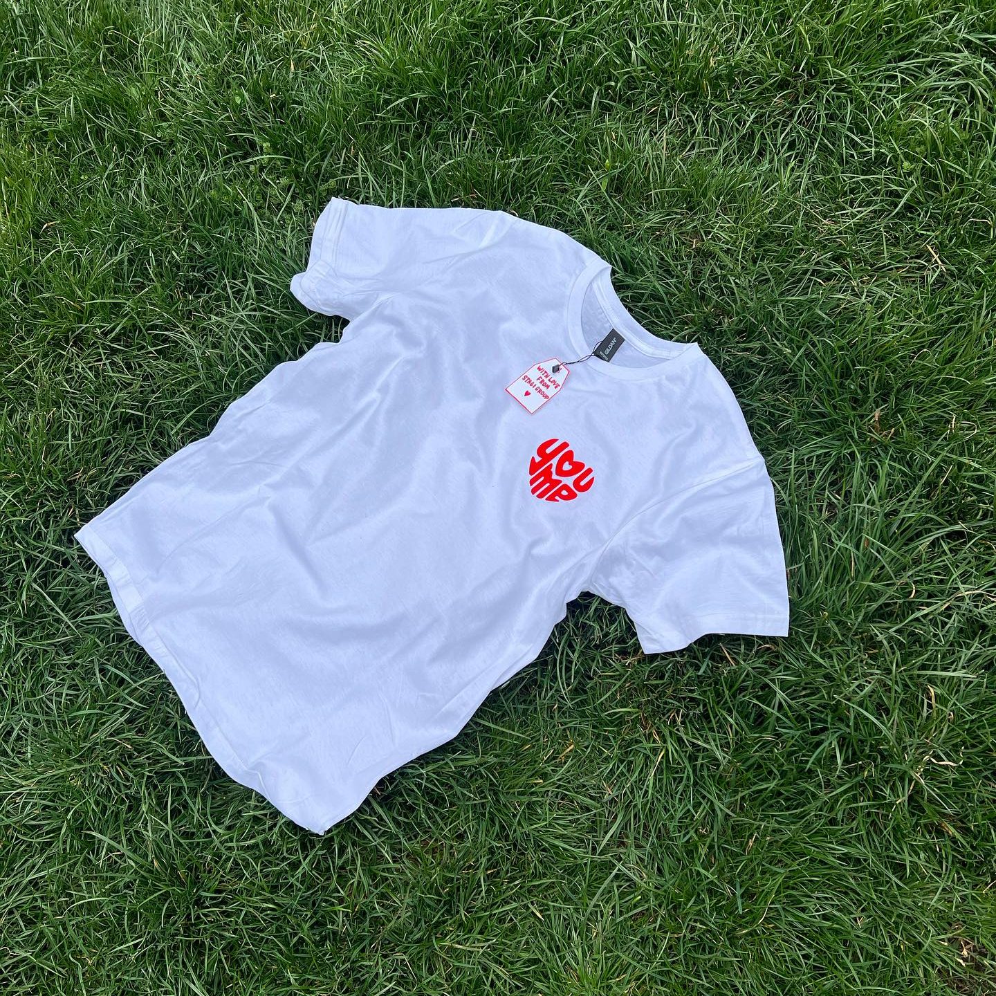 Stagi Group, სტაგი ჯგუფის თეთრი მაისური, წითელი წარწერა, YouMe, ხავერდის დიზაინი, ბალახის ფონზე